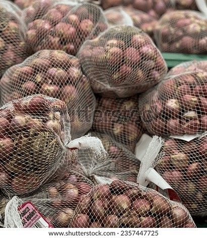 a photography of a bunch of onions in mesh bags on a table, grocery store display of onions and potatoes in mesh bags.