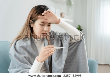 Young Asian woman having high fever while checking body temperature, female sneezing and runny nose with seasonal influenza, allergic, digital thermometer, virus, coronavirus, illness, respiratory
 Royalty-Free Stock Photo #2357452995