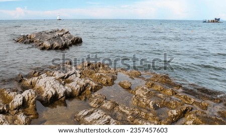 a photography of a boat is out in the water near rocks.