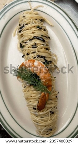 A picture of chilled aglio olio truffles from spaghetti angel hair neatly arranged on an oval plate with green edges topped with prawns and garnished with dill