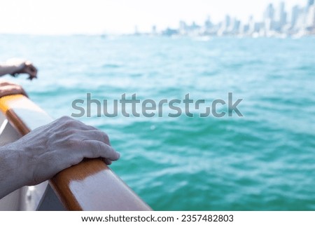 Person with hands on the railing of a boat looing at Toronto Skyline in Lake Ontario 