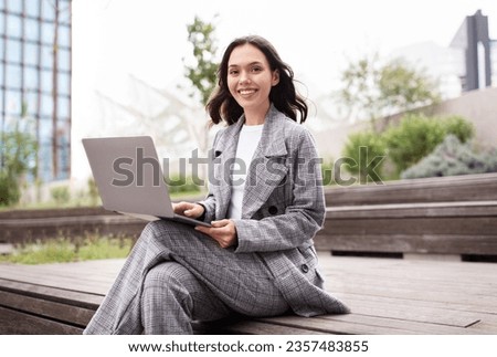 Successful Freelance. Happy young businesswoman using laptop computer, studying or working online outdoors, typing on pc while sitting in urban city area, smiling to camera. Website, internet offer