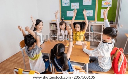 Multicultural group of students raising hand in class on lecture education, elementary school, learning people concept. Group team work of school kids with teacher sit in classroom floor raising hands Royalty-Free Stock Photo #2357500105