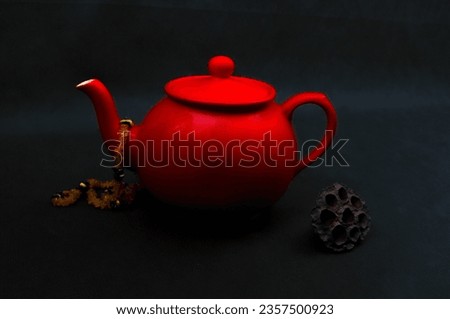 Red tea pot in a black background with a amber neckless hanging on it. Picture made with Nikon 300d.