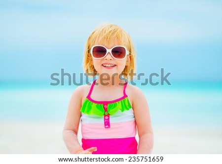 Portrait of happy baby girl in sunglasses on beach