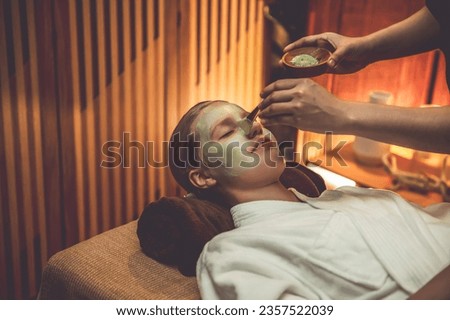 Serene ambiance of spa salon, woman customer indulges in rejuvenating with luxurious face cream massage with warm lighting candle. Facial skin treatment and beauty care concept. Quiescent Royalty-Free Stock Photo #2357522039