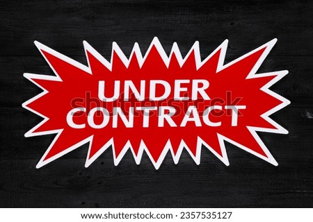 Red real estate sign with Under Contract in white on a black background. Real estate concept.
