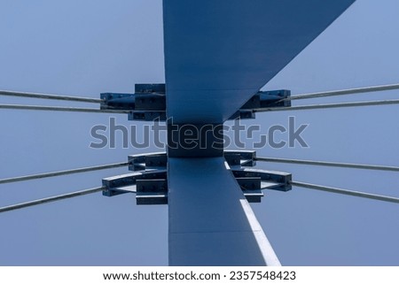 The culmination of the suspension bridge pylon. The top of the suspension bridge span on steel ropes against the blue sky . Royalty-Free Stock Photo #2357548423