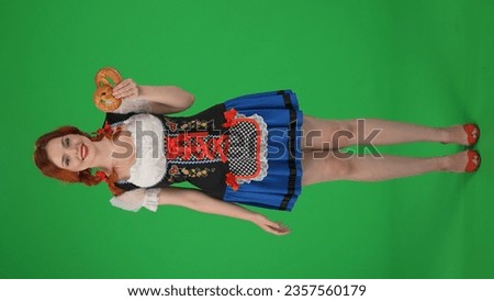 Full-size vertical green screen isolated chroma key shot of an excited young German woman, waitress holding a pretzel, smiling sincerely.