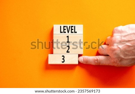 Time to level 3 symbol. Concept word Level 1 2 3 on wooden block. Businessman hand. Beautiful orange table orange background. Business planning and time to level 3 concept. Copy space. Royalty-Free Stock Photo #2357569173