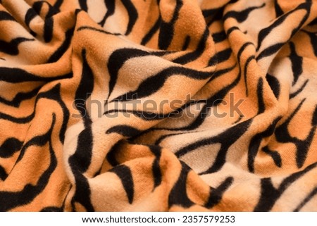 Wavy fabric with tiger print, bright yellow with black stripes. Popular fabric from the skin of wild animals for bright women, close up