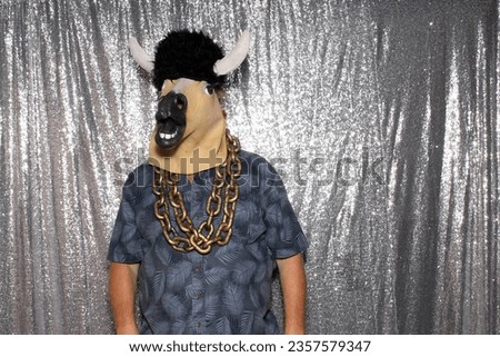 Photo Booth. A man wearing a Rubber Horse Head Mask poses and holds Props while he has his Pictures taken while in a Photo Booth. Photo Booths are love by people at parties and events around the world