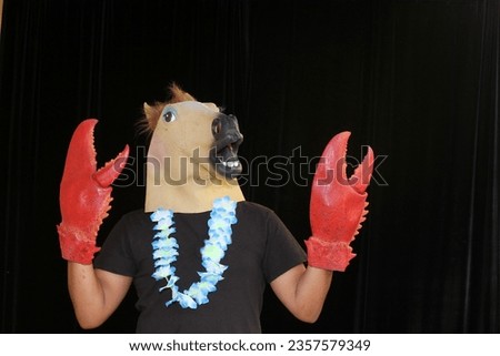 Photo Booth. A man wearing a Rubber Horse Head Mask poses and holds Props while he has his Pictures taken while in a Photo Booth. Photo Booths are love by people at parties and events around the world