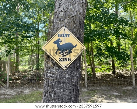 A goat crossing sign attached to a tree.