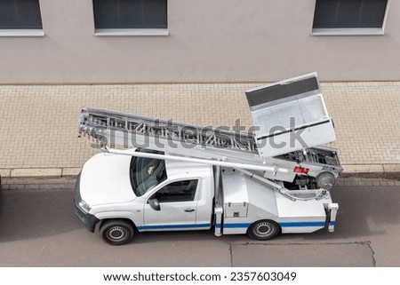 Mover service lifting ladder cargo crane platform vehicle van parked at city street. Retractable furniture elevator machine car pickup truck rental company for relocation and house moving delivery Royalty-Free Stock Photo #2357603049