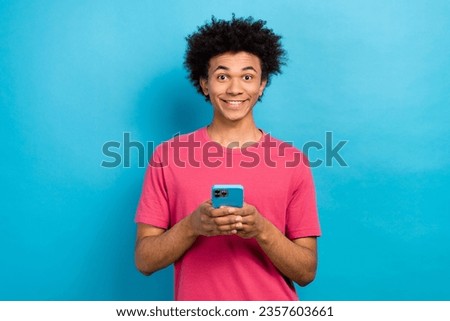 Photo of funky cheerful guy user wear trendy pink clothes hold modern iphone isolated on blue color background
