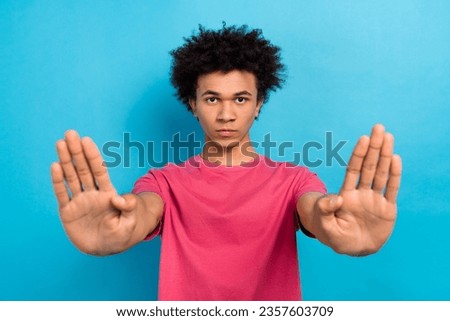 Portrait of assertive serious guy with afro hairdo dressed stylish t-shirt stretching palms stopping you isolated on blue color background