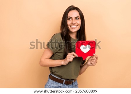 Photo of pretty tricky lady wear khaki t-shirt holding feedback card looking empty space isolated beige color background