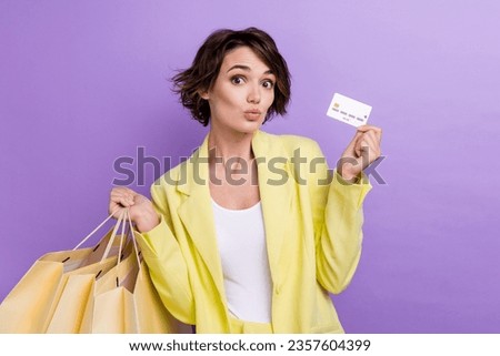 Photo of cheerful shocked woman dressed yellow jacket lips pouted plump kiss rising bank card shoppers isolated purple color background