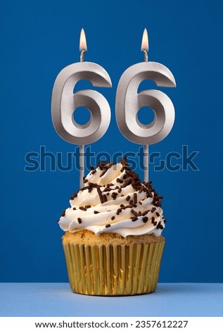 Vertical birthday card with cake - Lit candle number 66 on blue background Royalty-Free Stock Photo #2357612227