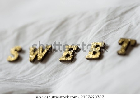 the word "sweet" isolated close-up on soft white fabric