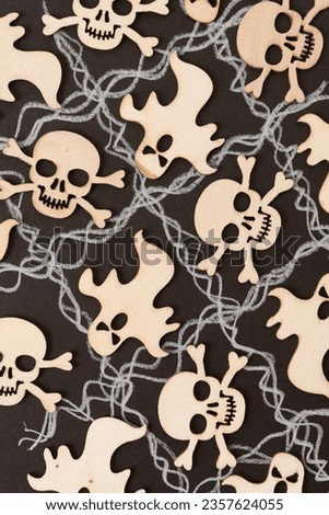 laser-cut ornaments or shapes 
 of skull and crossbones and goblins arranged on black paper with wavy lines