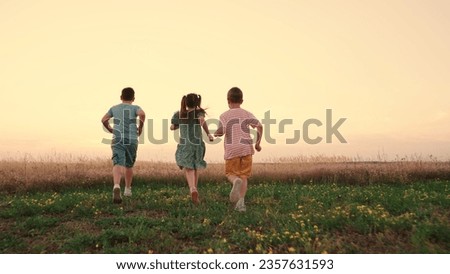 Happy childhood. Teenagers play running. Funny children play in park, friends run in summer. Child run on grass, sunset. Happy boy, girl run in field, playing in nature. Family, weekend outdoors. Royalty-Free Stock Photo #2357631593