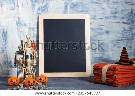 Skeletons sit in a tin can next to a black photo frame with pumpkins. Congratulations on Halloween. Space for text. Minimalistic layout.