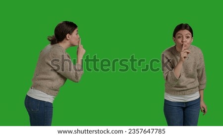 Private woman doing hush symbol to keep silence and secret over greenscreen backdrop, expressing privacy and secrecy on camera. Female model showing confidential and silent gesture, doing shh sign.