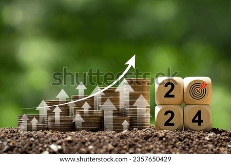 Coins stack with trading chart and wooden cube 2024 in financial concepts and financial investment business stock growth. Business cost and budget planning for a new year.investment goals in 2024