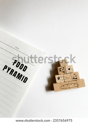 Basic food pyramid on wooden cube and notebook with food pyramid text on white background. Template signs for healthy eating diet concept