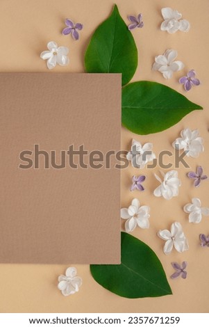 Composition with empty envelope and beautiful spring lilac flowers on beige background. Mockup card invitation greeting card postcard copy space template. Branches of lilac blooming bouquet. 