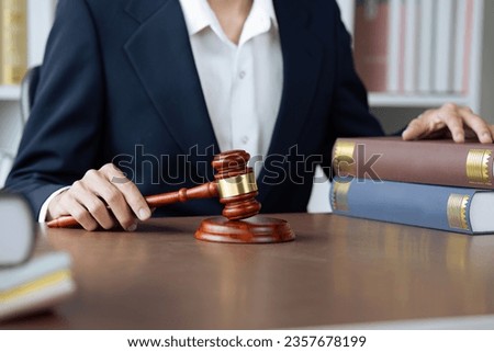 The young lawyer is reading book and holding legal gavel on an office table