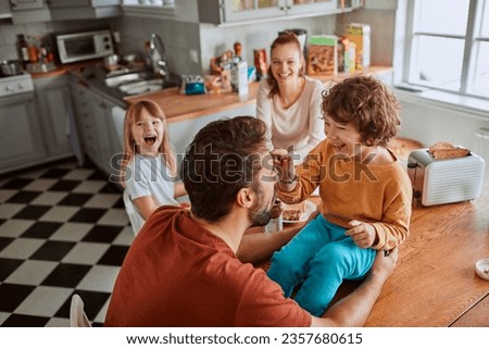 Young family having breakfast together and being messy in the kitchen Royalty-Free Stock Photo #2357680615