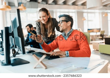 Young coworkers using the computer in a startup company office Royalty-Free Stock Photo #2357686323