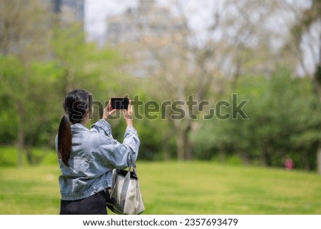 Woman use mobile phone to take photo at park