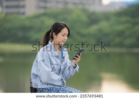 Young woman look at mobile phone at lakeside