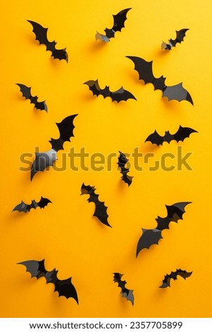 Capture the essence of your Halloween event. Vertical top view of flying bats on yellow backdrop, offering space for your wording or ad