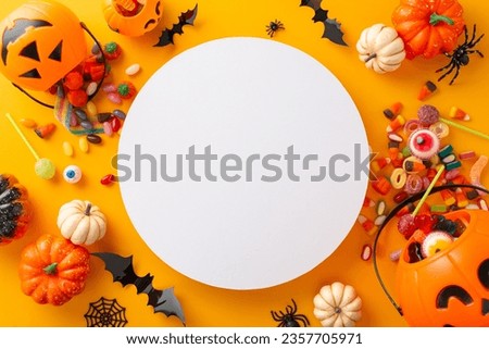Fun kid's trick or treat tradition on Halloween night. Top view photo of pumpkin basket with sweets and Halloween decorations on yellow isolated background with copy-space for text or advert