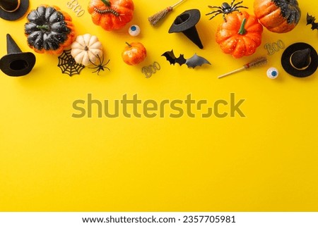 Commemoration of eerie Halloween evening idea. High-angle shot displaying pumpkins, eyes, witch hats, brooms and other decor on yellow isolated backdrop. Perfect for advertising or text incorporation