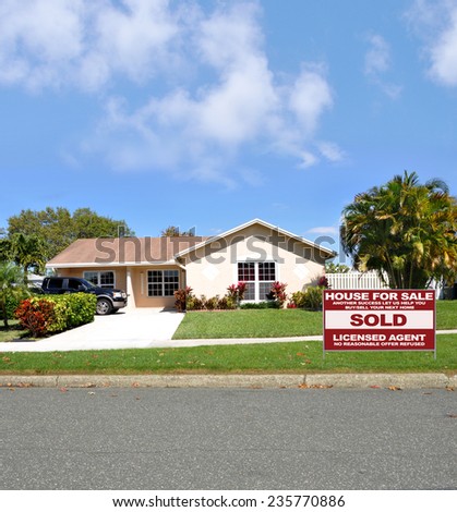 Real Estate sold (another success let us help you buy sell your next home) sign suburban ranch style home sunny residential neighborhood blue sky clouds USA