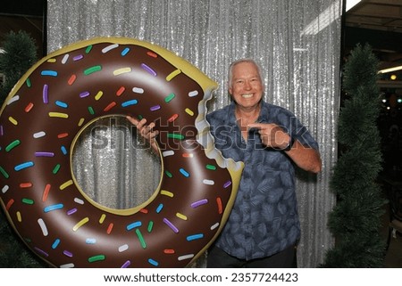 Donut. Photo Booth. A man smiles and poses with a Giant Inflatable Donut while having his pictures taken in a Photo Booth. People love Photo Booths at Weddings and Parties around the world. Enjoy. 