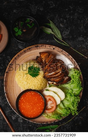 Image of Chicken Rice on a black glass table decorated with some leaves and spoons