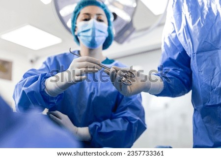 Low Angle Shot in the Operating Room, Assistant Hands out Instruments to Surgeons During Operation. Surgeons Perform Operation. Professional Medical Doctors Performing Surgery. Royalty-Free Stock Photo #2357733361