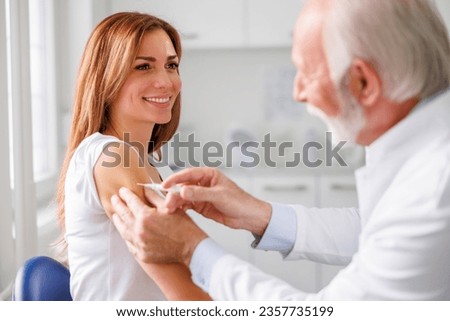 Young woman getting seasonal flu vaccine in healthcare facility - vaccination, immunization and disease prevention concept. Doctor vaccinating patient Royalty-Free Stock Photo #2357735199
