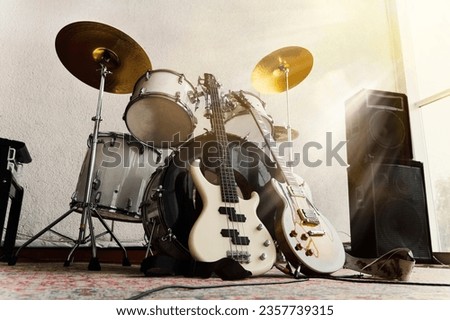 Rock and roll band instruments. Electric guitar, bass guitar and rams in the recording studio and in the rays of bright sunlight. Royalty-Free Stock Photo #2357739315