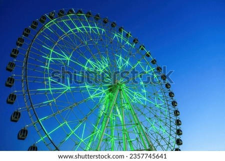 High neon ferris wheel at nighttime in an amusement park Navruz or Anhor in Tashkent, Uzbekistan.