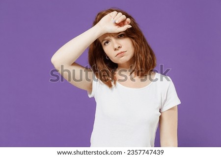 Young tired exhausted troubled sick ill confused caucasian woman 20s wear white basic blank print design t-shirt put hands on head having headache isolated on dark violet background studio portrait. Royalty-Free Stock Photo #2357747439