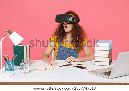 Shocked african american girl employee in office sit work at desk isolated on pink wall background. Achievement business career. Education in school university college concept. Watching in headset