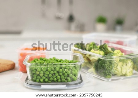 Containers with green peas and fresh products on white table, space for text. Food storage Royalty-Free Stock Photo #2357750245